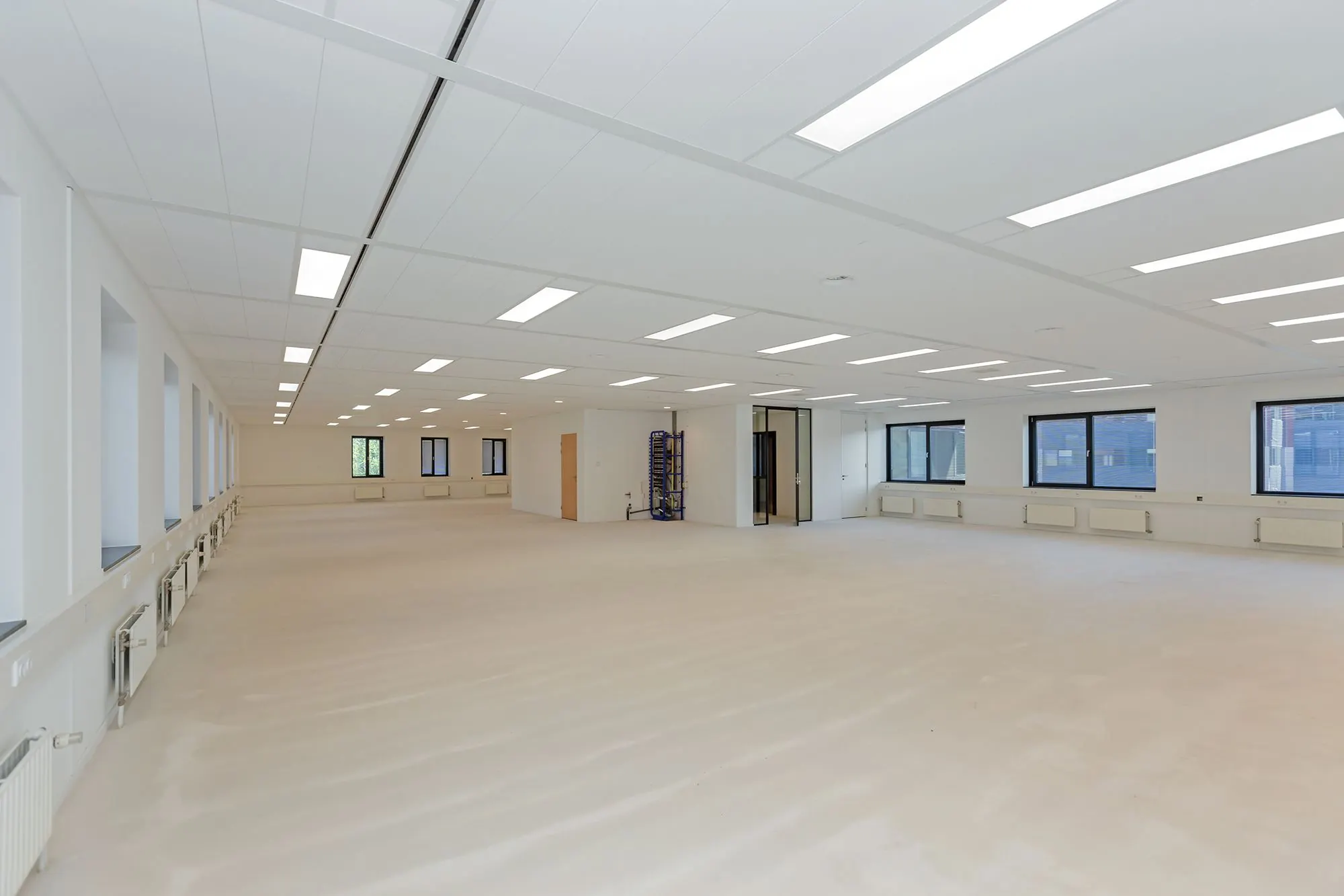 Ruime, leegstaande kantoorruimte aan de Boris Pasternaklaan met strakke witte wanden, grote ramen en systeemplafond met ledverlichting.